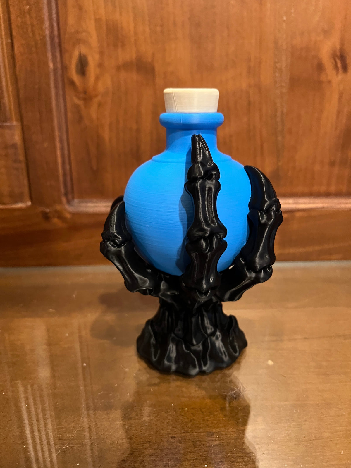 Blue decorative potion bottle held by a black skeletal claw