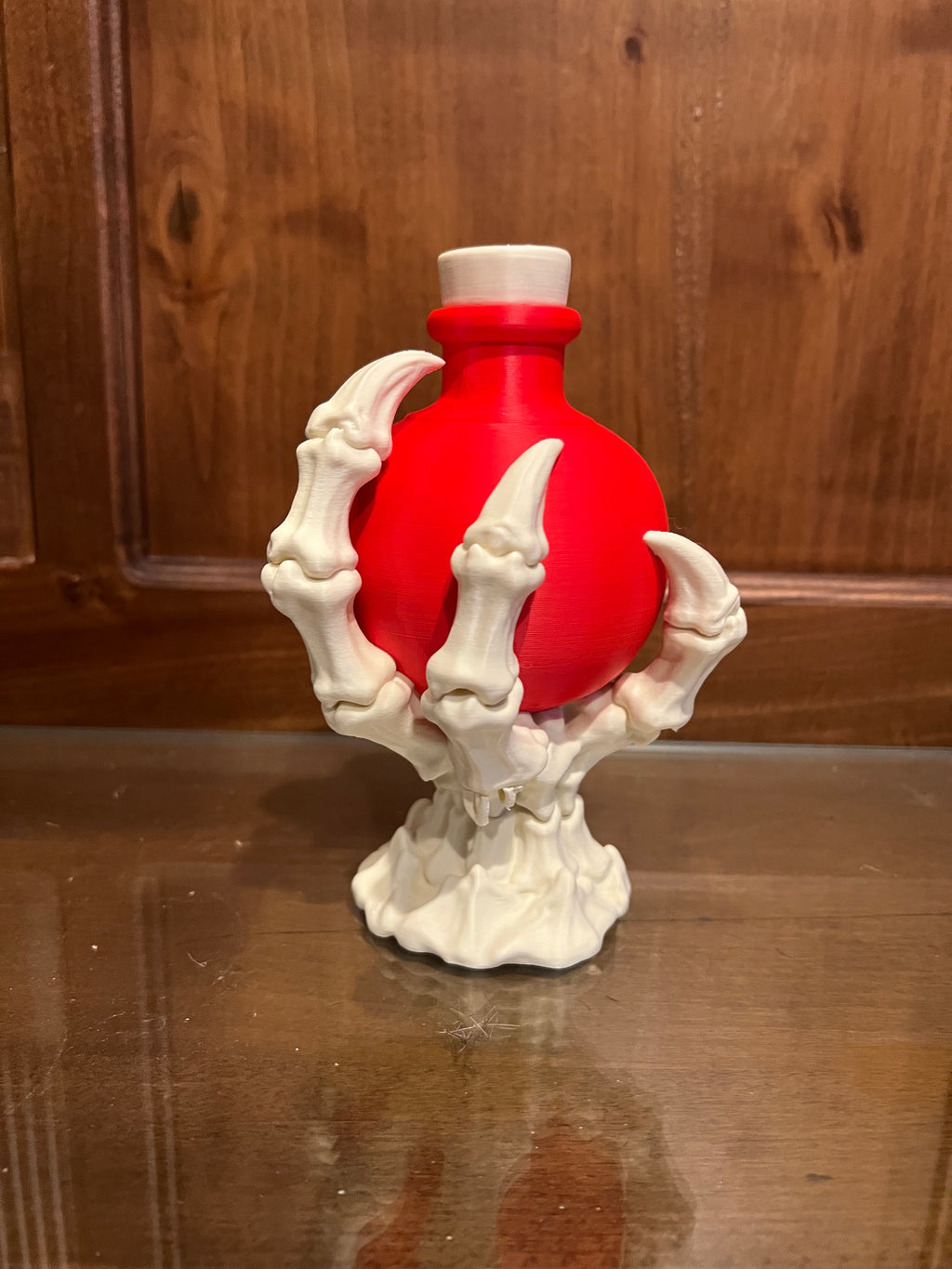 Red decorative potion bottle held by a bone white skeletal claw