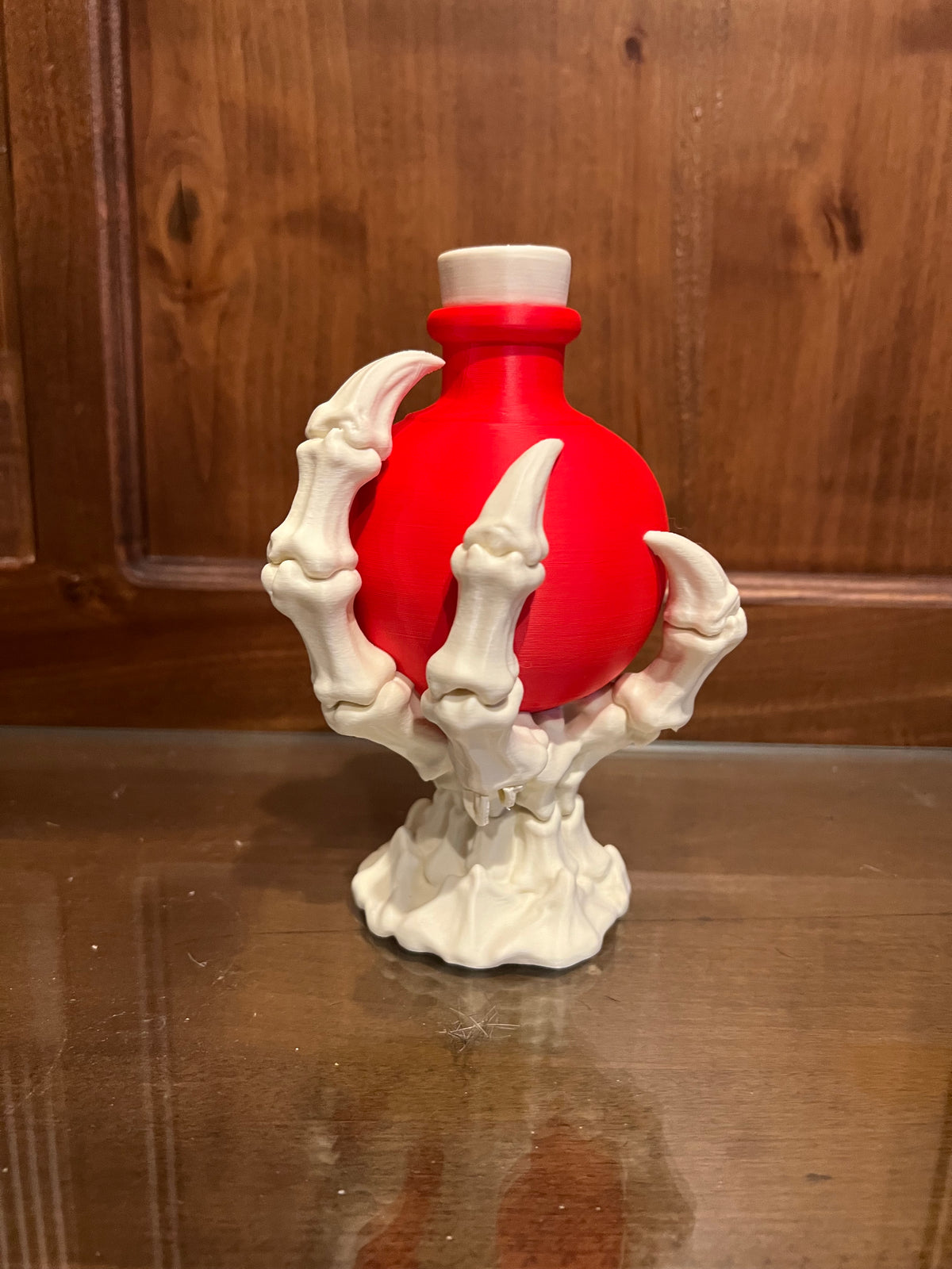 Red decorative potion bottle held by a bone white skeletal claw
